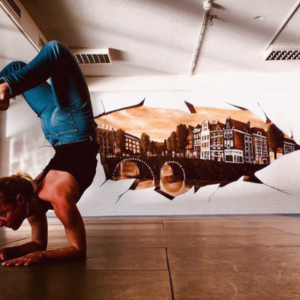 Frau in Yoga-Position vor Wand mit Graffiti
